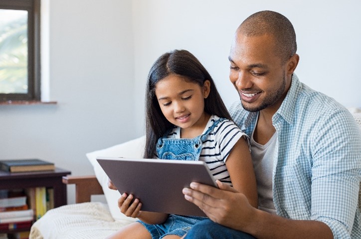 Father helping daughter on tablet device